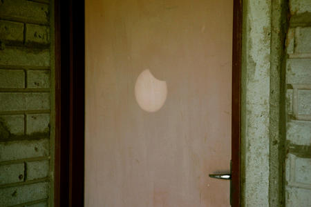 Pinhole projection of the sun on a door